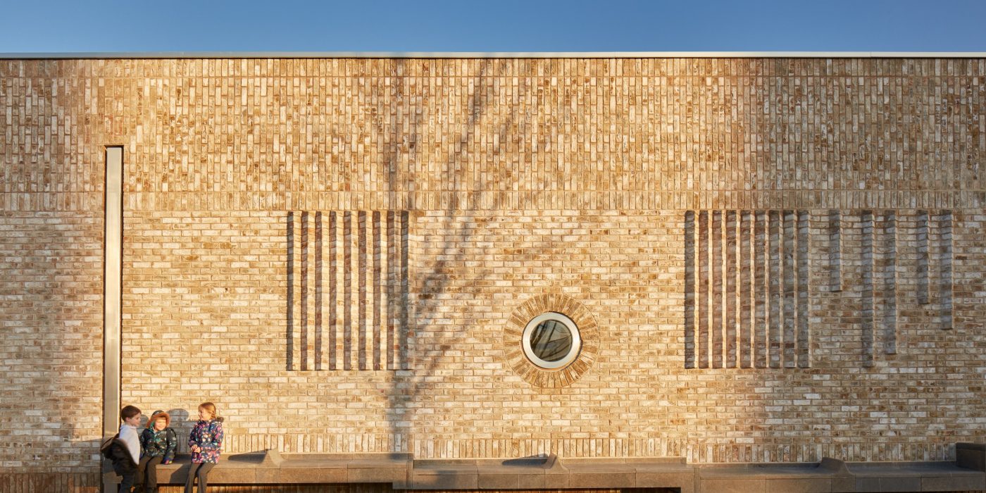 Three children sitting outside Storey's Field contemporary brickwork architecture