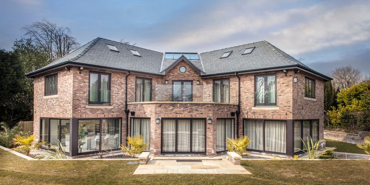 Large modern house with large windows and brick walls with garden