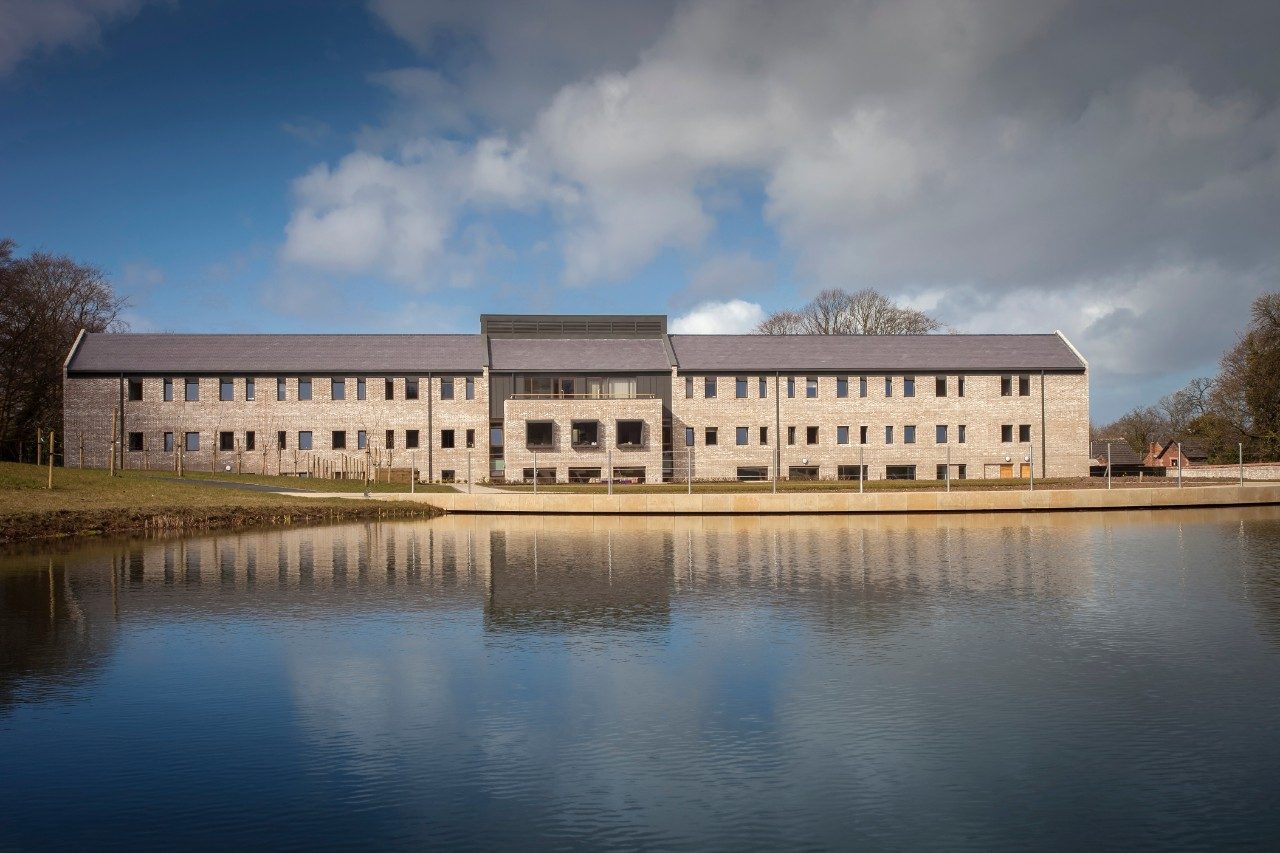 View across a lake of a modern monastery