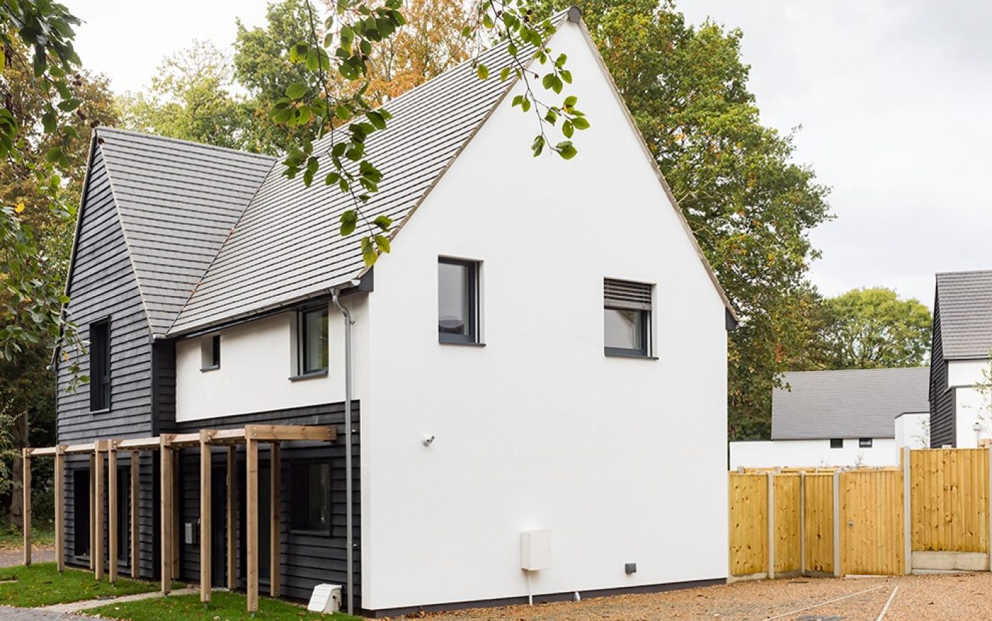 White modern house with trees and wooden fence