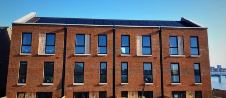 Row of four modern terraced houses against blue sky