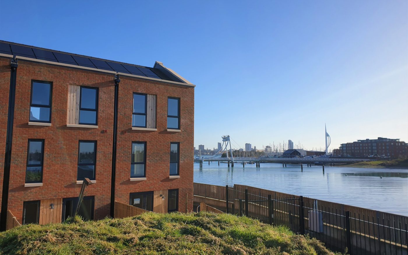 image of the end of a row of modern terraced houses overlooking a river and bridge
