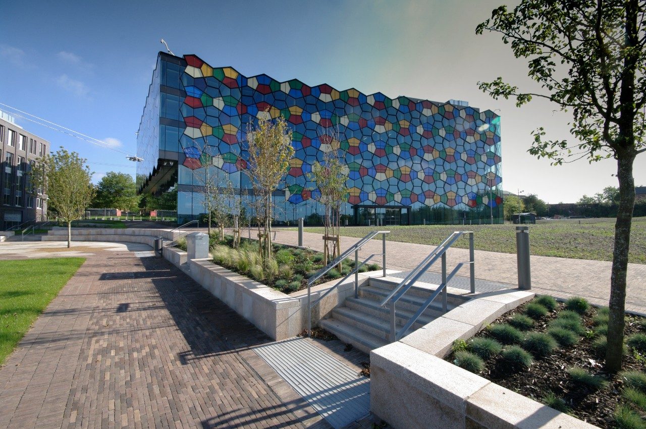 Modern multi-coloured glass building with paved outside area