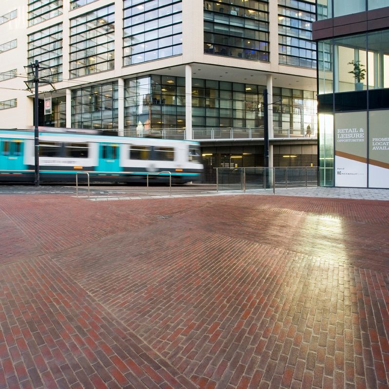 Tram going past clay paved piazza
