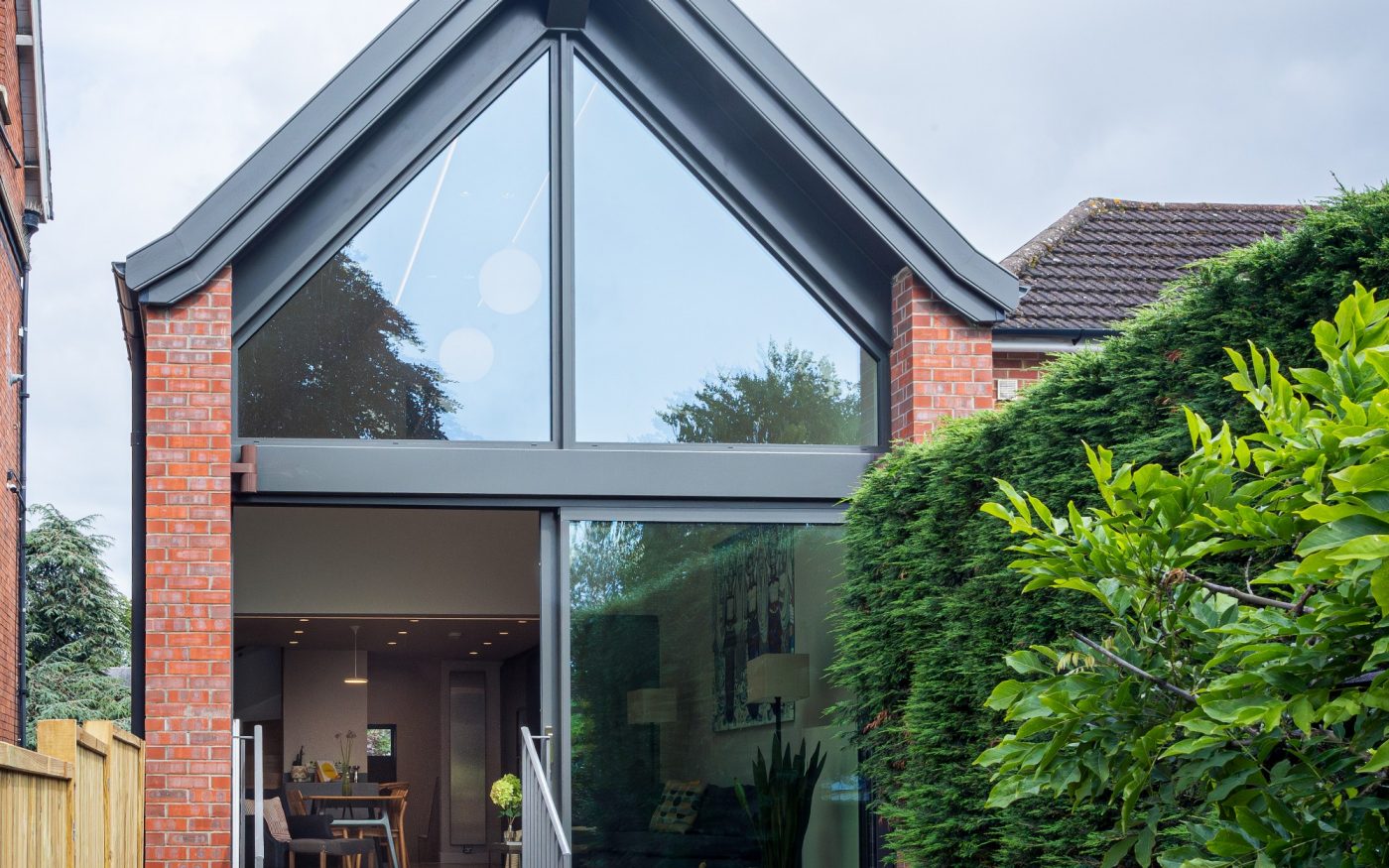 back entrance of contemporary home with large green bushes