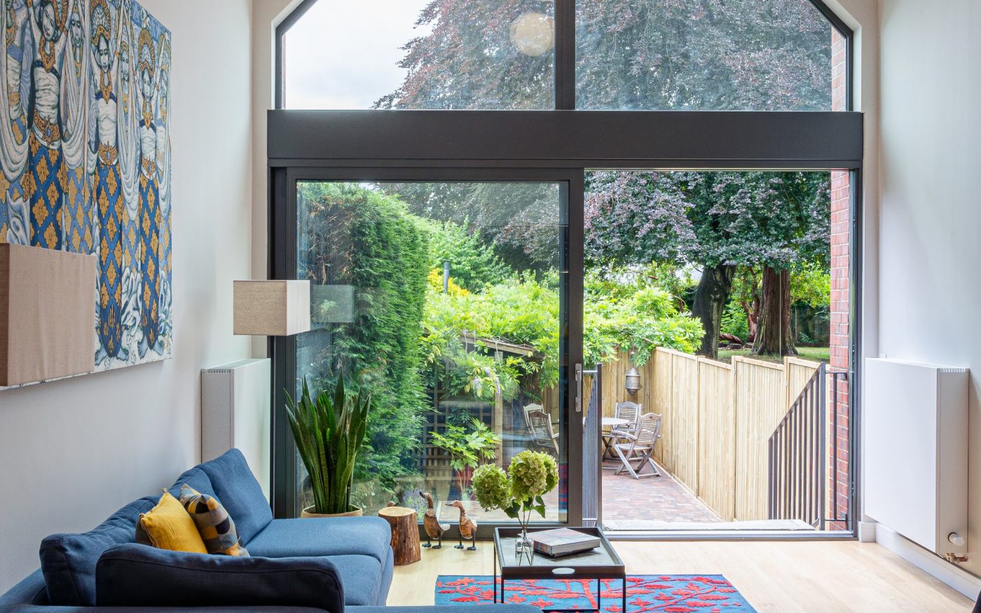 Internal view looking out of large window into green garden