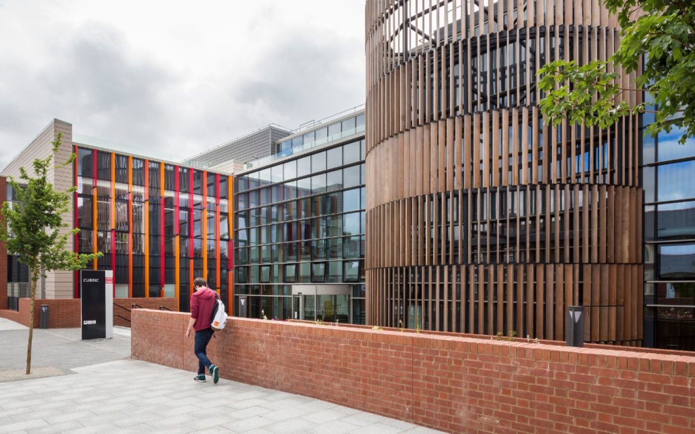 Man walking past the entrance of the CUBRIC building