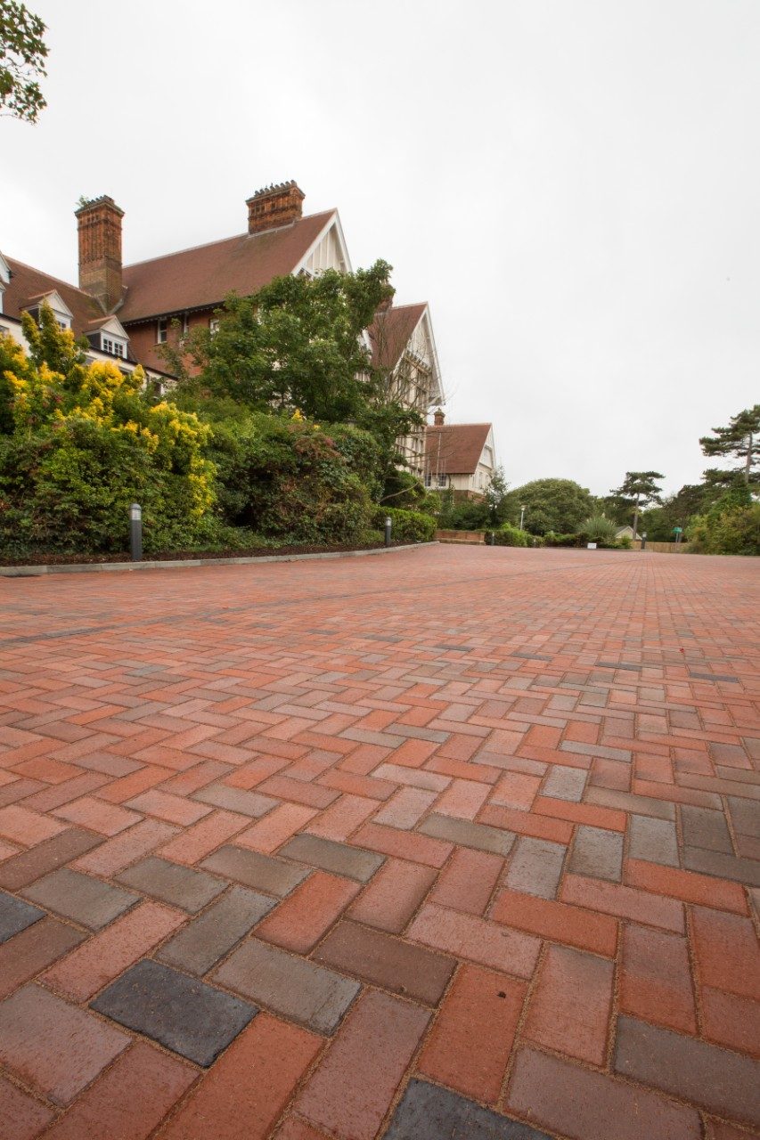 Herringbone paving in front of large house and trees