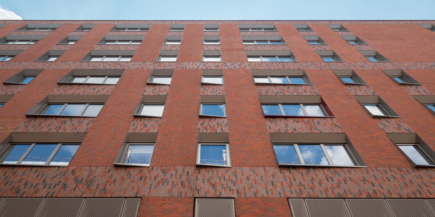 Exterior of modern red brick apartment building against blue sky