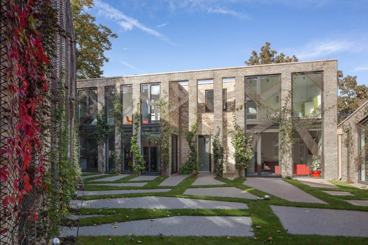 Sun shining on modern brick house with large windows and paved courtyard area
