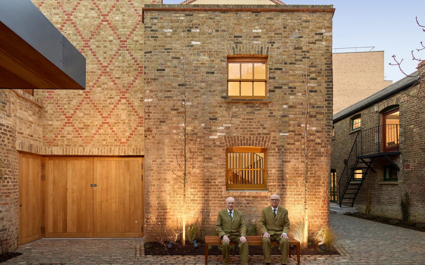 Gibert and George sat on a wooden bench outside the gallery