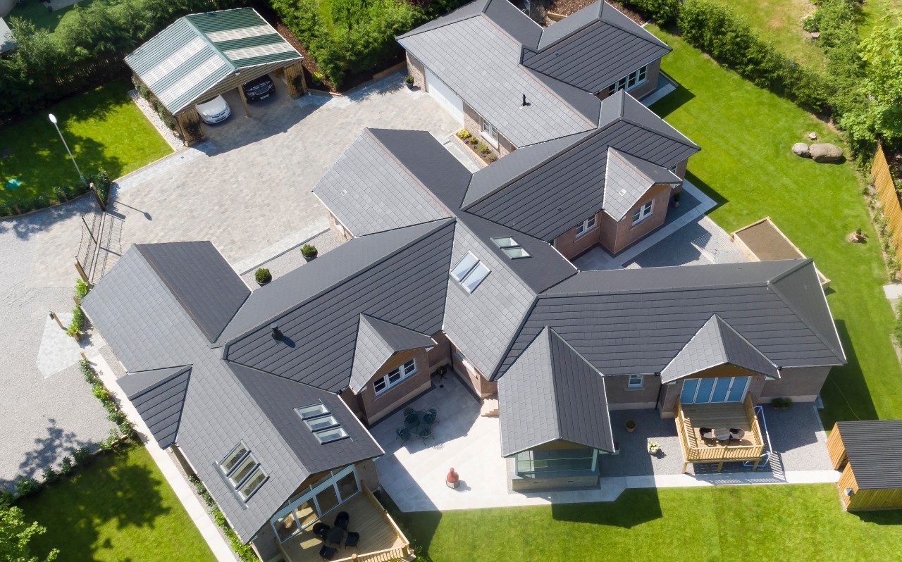 Aerial view of grey roof on large building with green lawns