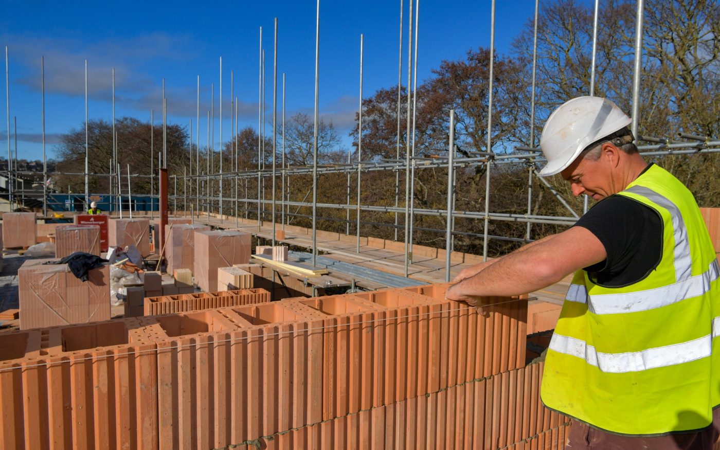 Man in PPE laying Porotherm clay blocks on building site
