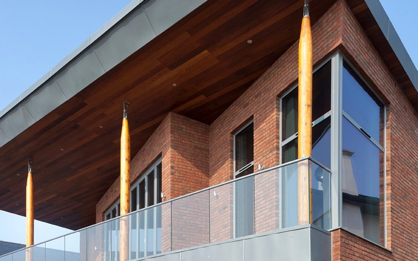 Glass balcony and wooden beams on modern brick home