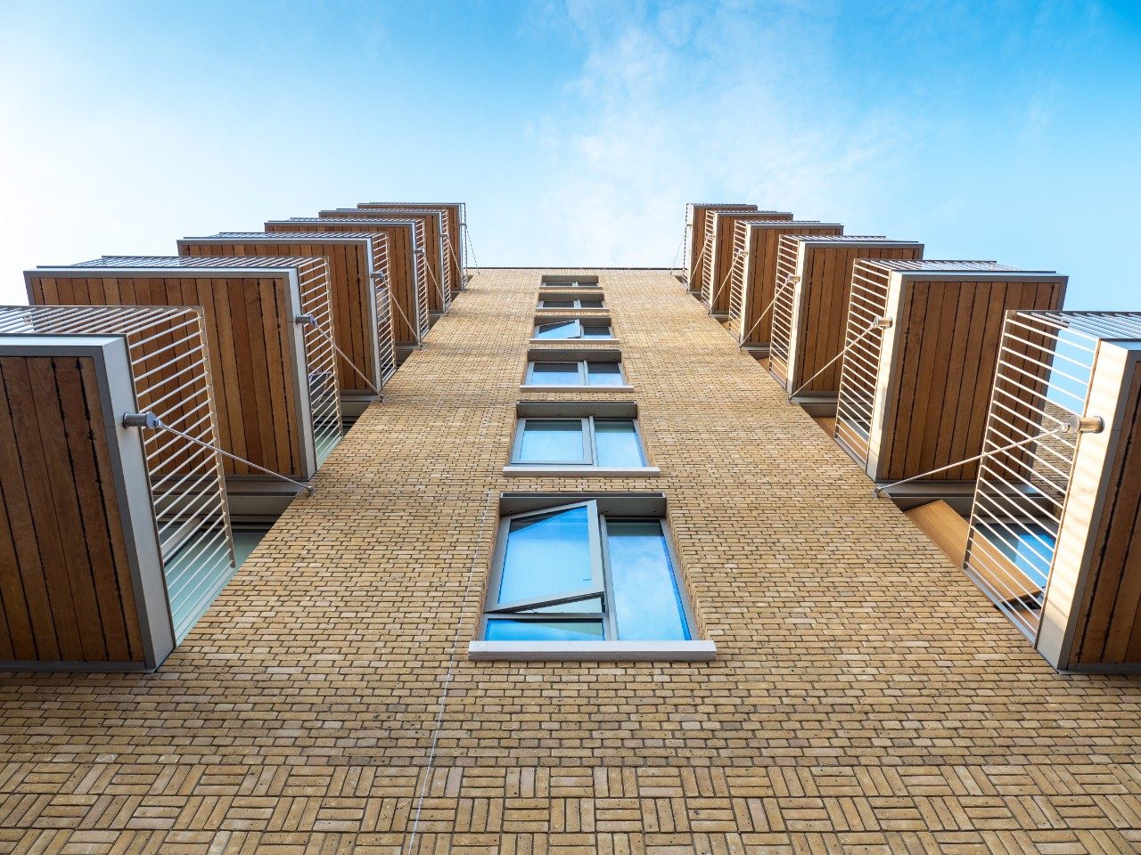 Looking up at yellow brick apartment building with balconies