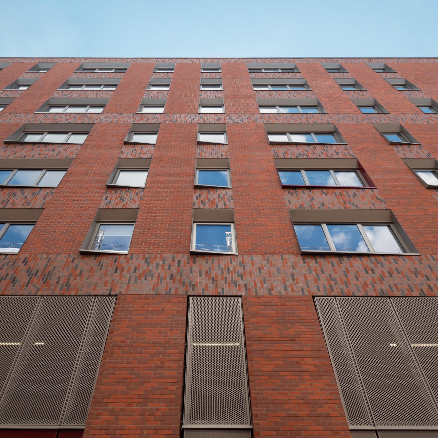 Exterior of modern red brick apartment building against blue sky