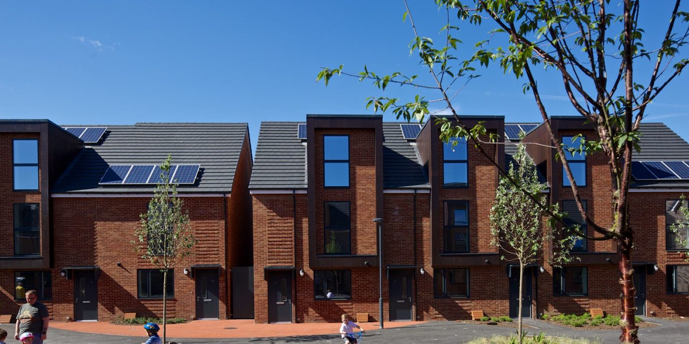 Modern social housing development with two children playing on bikes outside