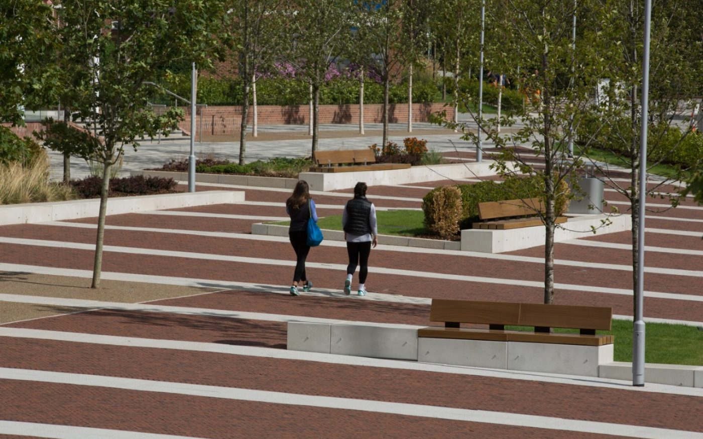 Two students walking across university campus with paved area