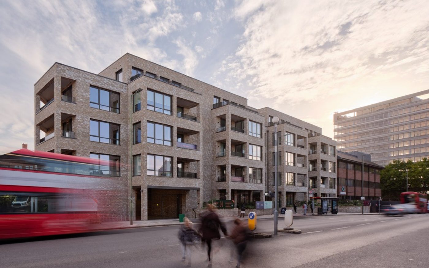 multi-storey new build building on a busy London street and a red bus going past