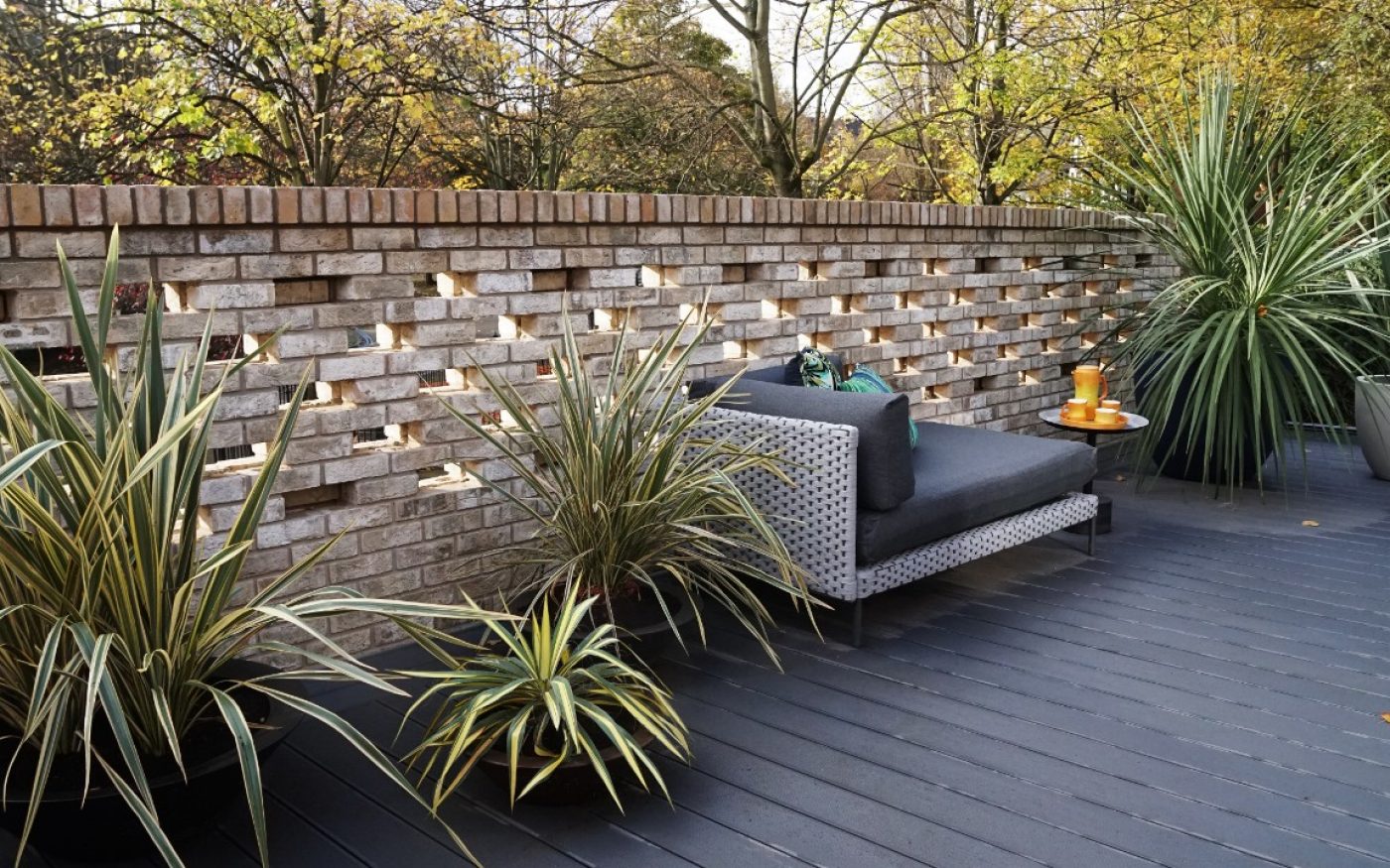 Modern garden with decking and brick wall with large plants