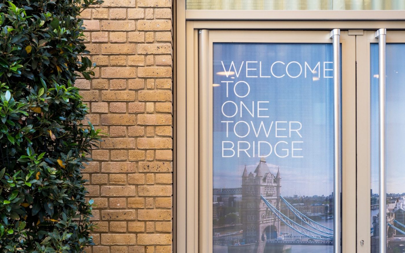 'Welcome to One Tower Bridge' text on window of the building