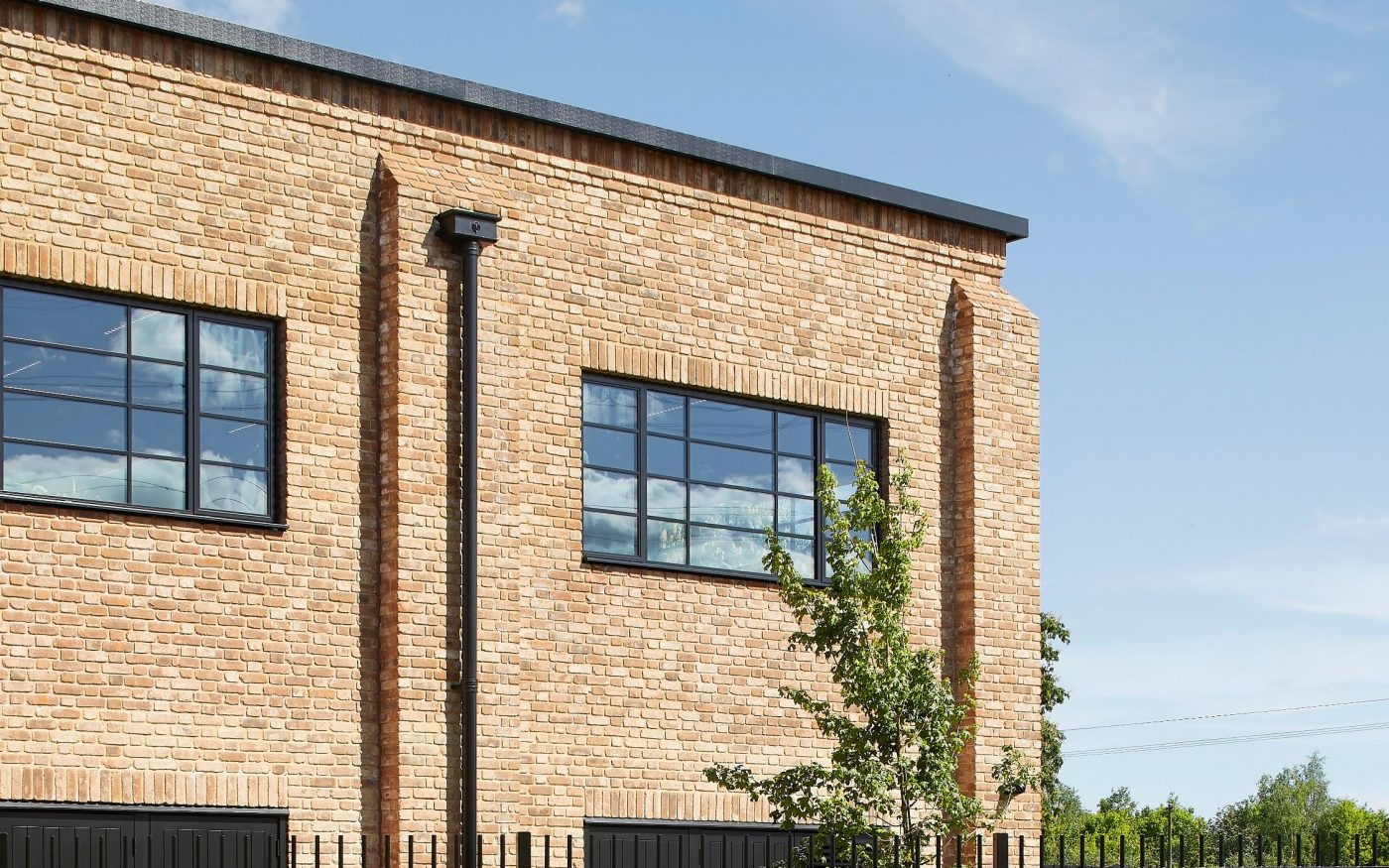 modern industrial-style building with light brown brick walls and large black-framed windows