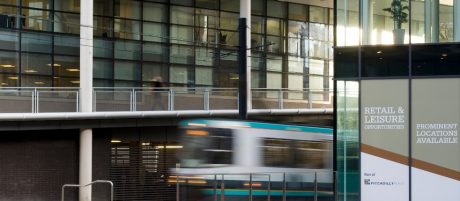 Train driving through Piccadilly Place in Manchester