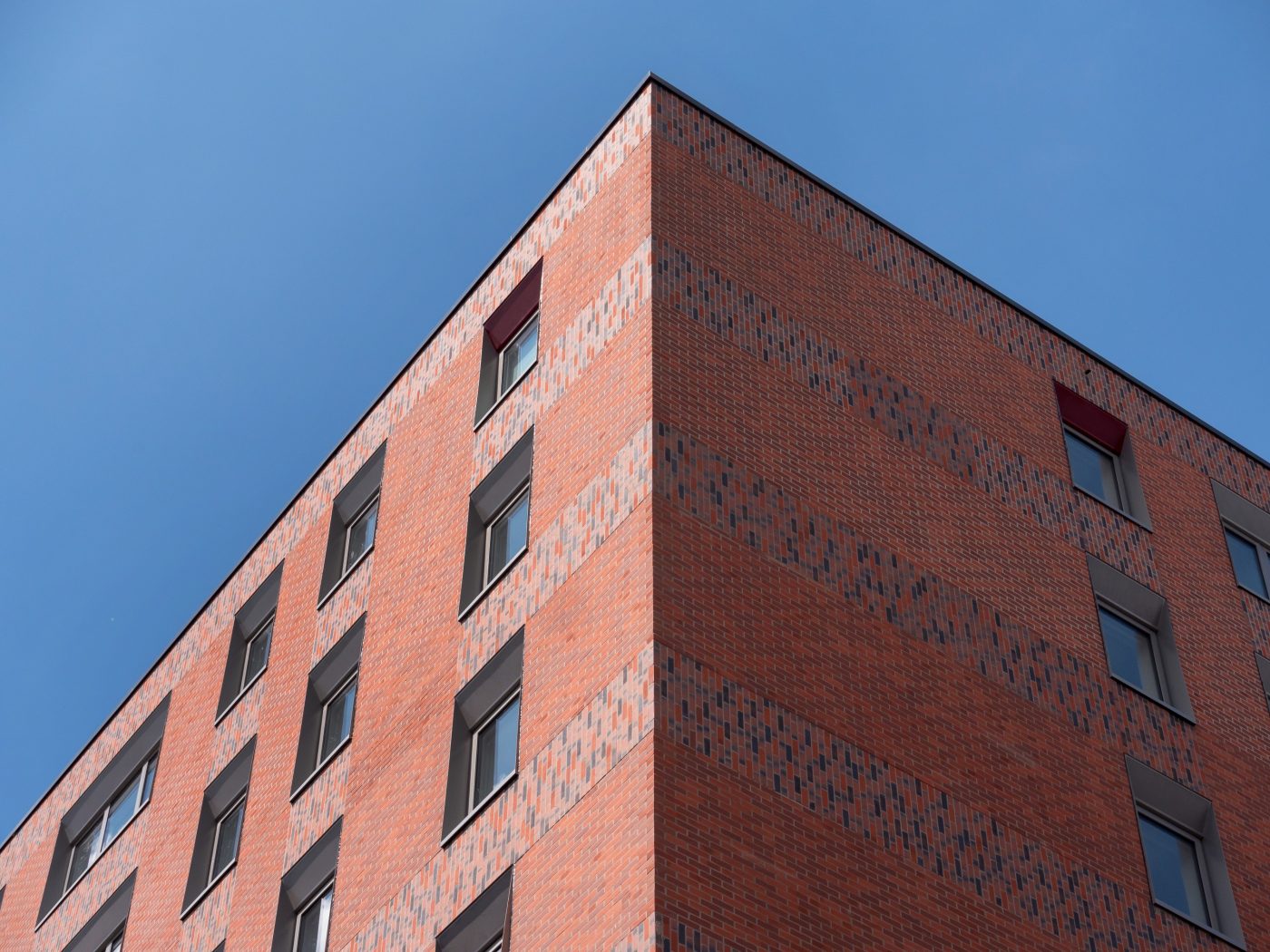 Corner of modern red brick building against clear blue sky