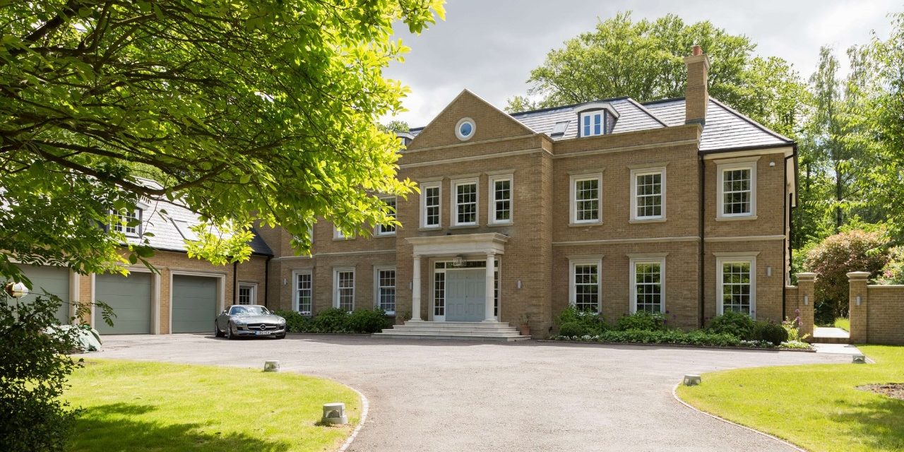 Large modern house in traditional style with driveway and trees