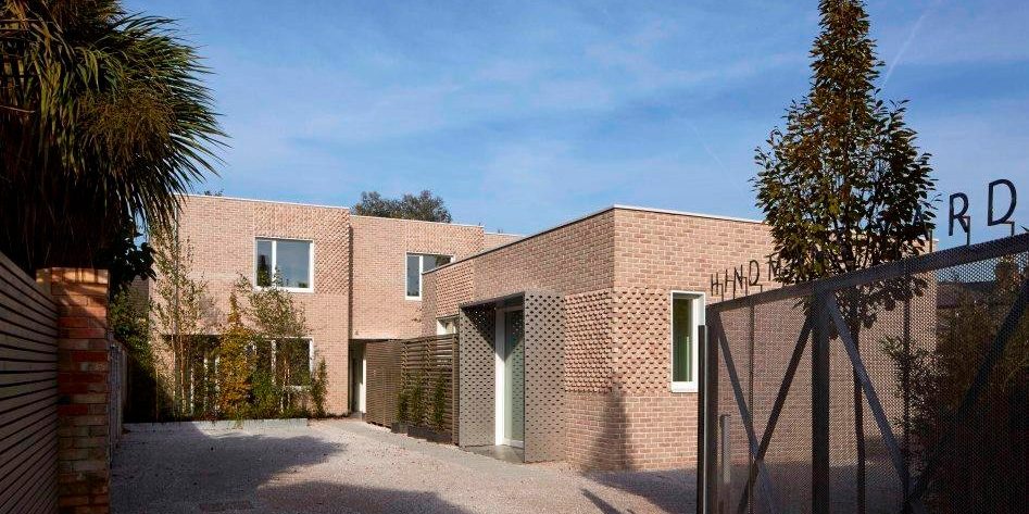 Open gate to modern brick home against blue sky