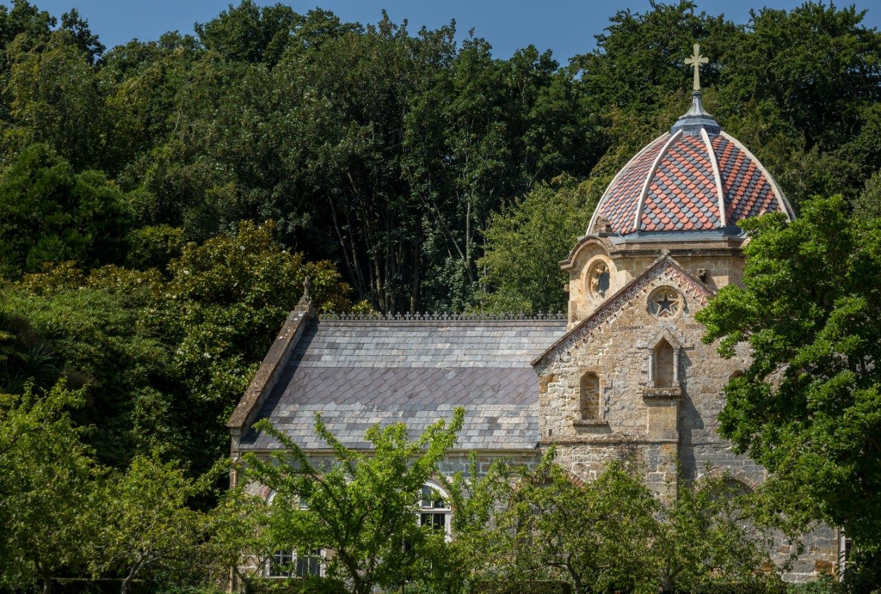 Domed roof of historic church appearing through green trees