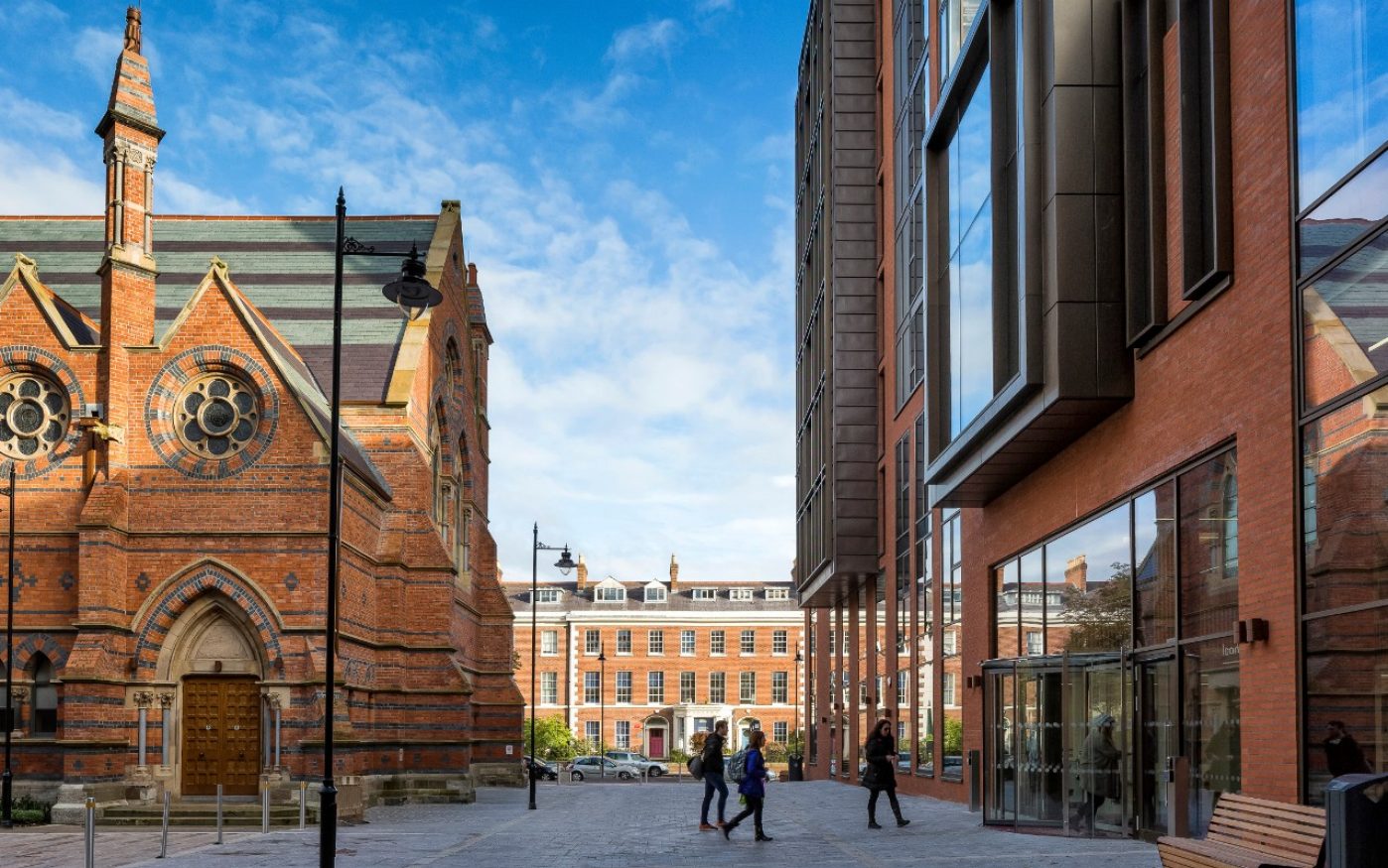 People walking between old brick church and modern brick building