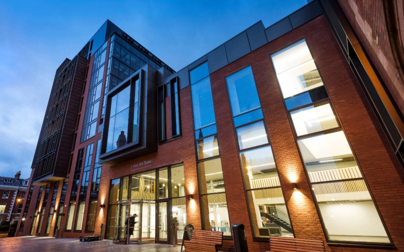 Exterior of modern building at Queen's University Belfast, lit up at night time