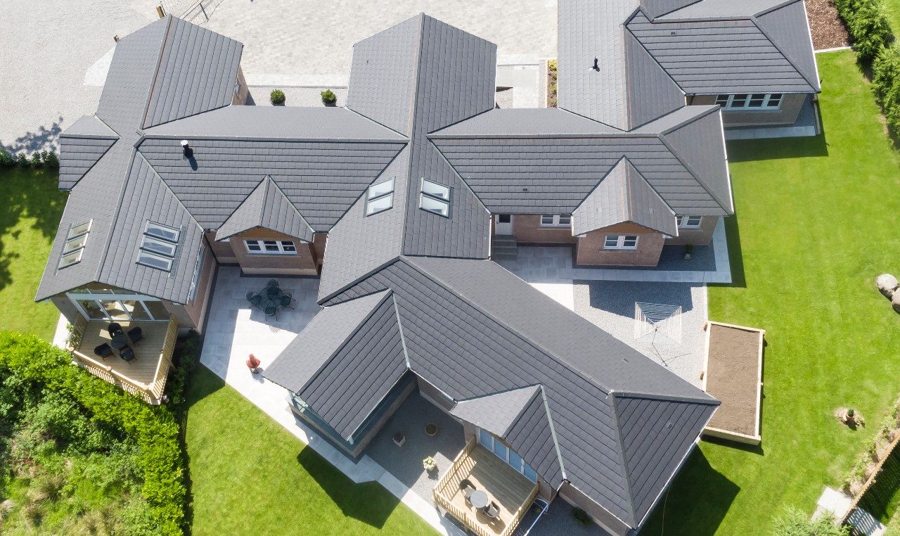 Aerial view of new build house with grey roof tiles and green lawns