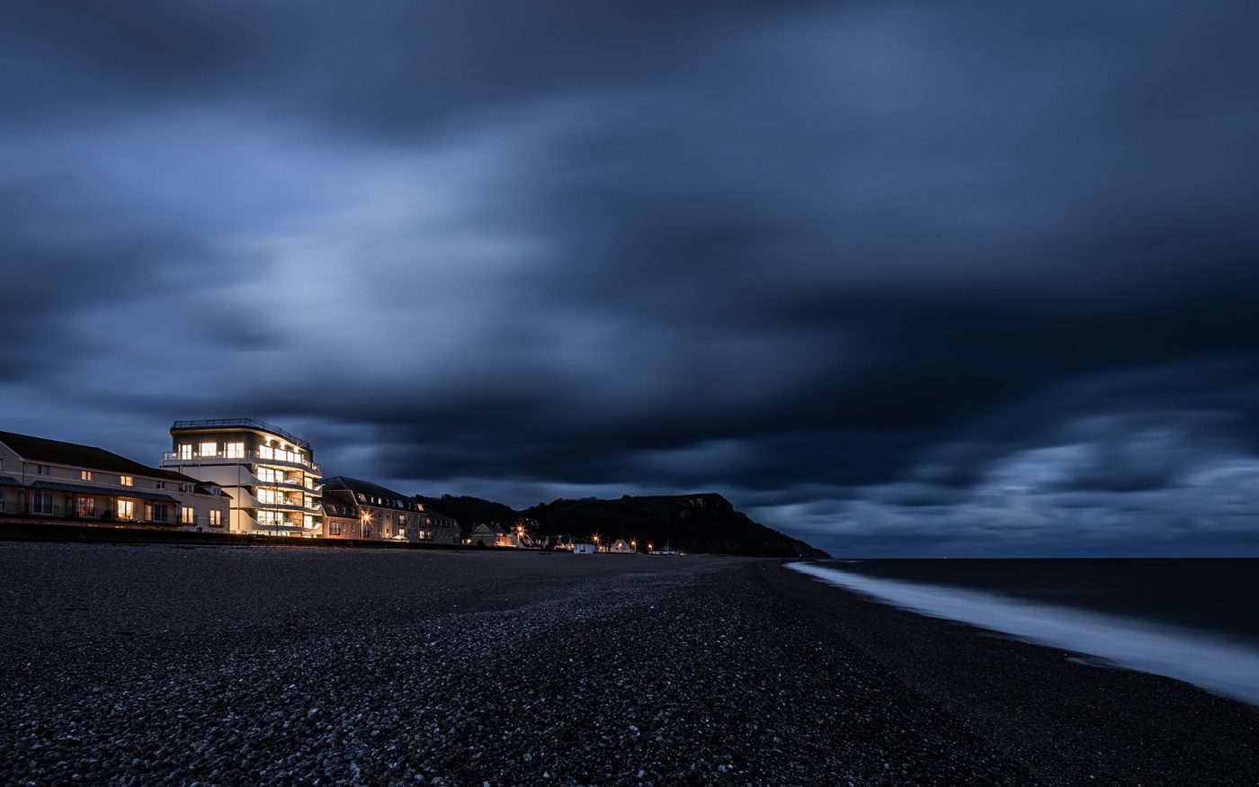 Seaton Beach building lit up in the distance from the beach at night