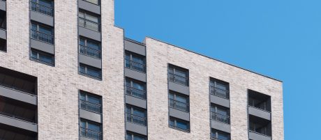 Windows and balconies on modern apartment building against blue sky