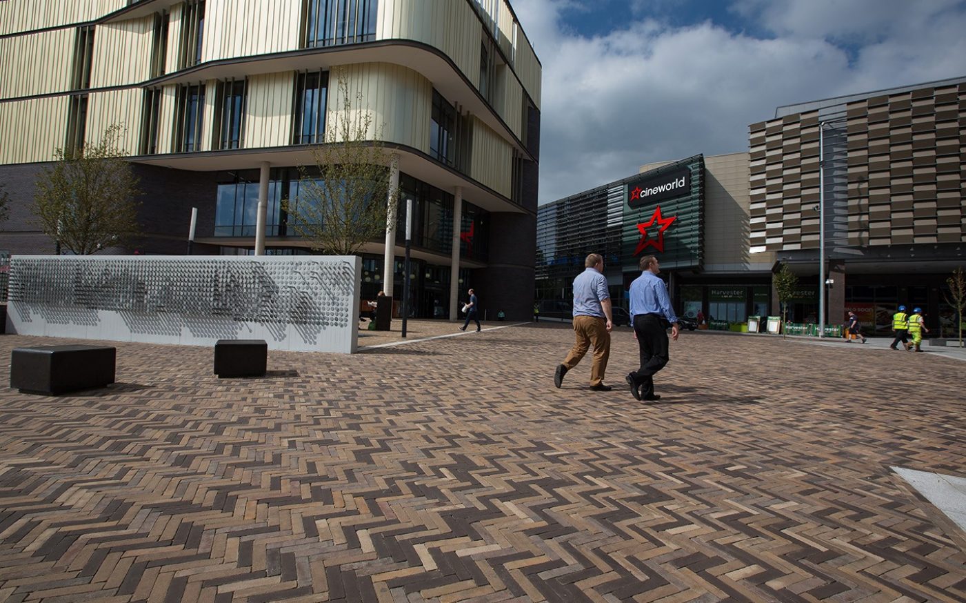 Two men walking past shops and cinema at a retail park