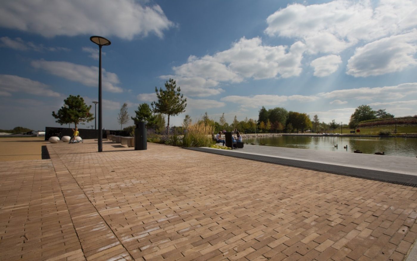 Wide paved path next to a lake on a sunny day