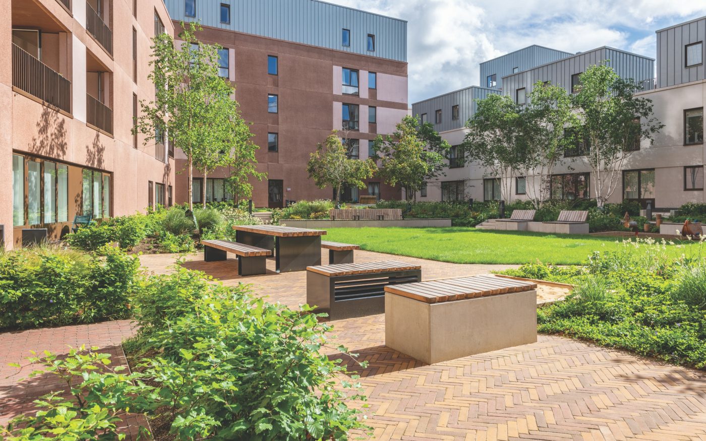 Paved social space in courtyard of residential building with greenery surrounding