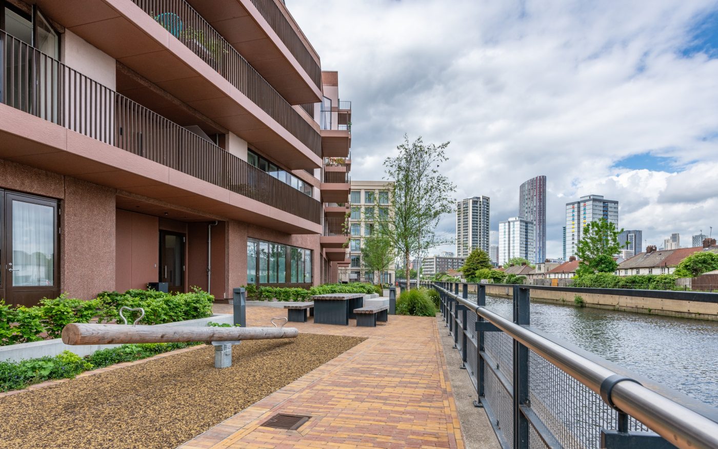 Paved pathway with Residential Building on left hand side and a river on the right