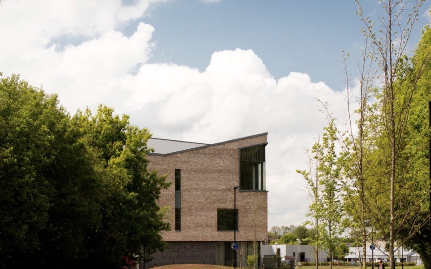 Green lawn and trees with modern angular building in the distance