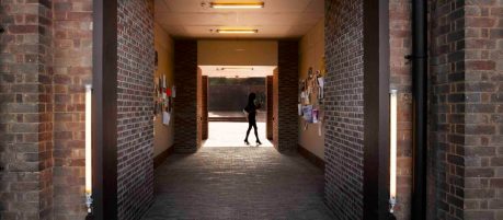 women walking past down a dark brick paved corridor