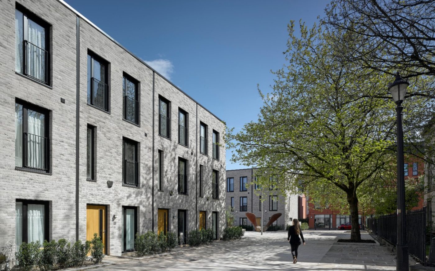 Modern terraced housing made from grey brick with yellow door