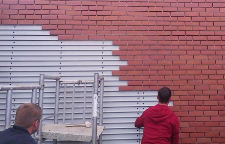 Two men installing Corium brick tile cladding