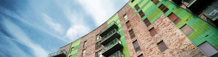 Looking up at a Corium brick clad building with green tiles