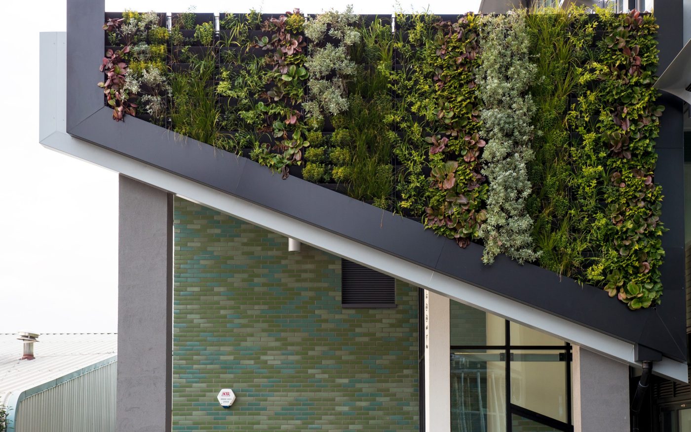 Close up of green glazed brick tiles and living wall