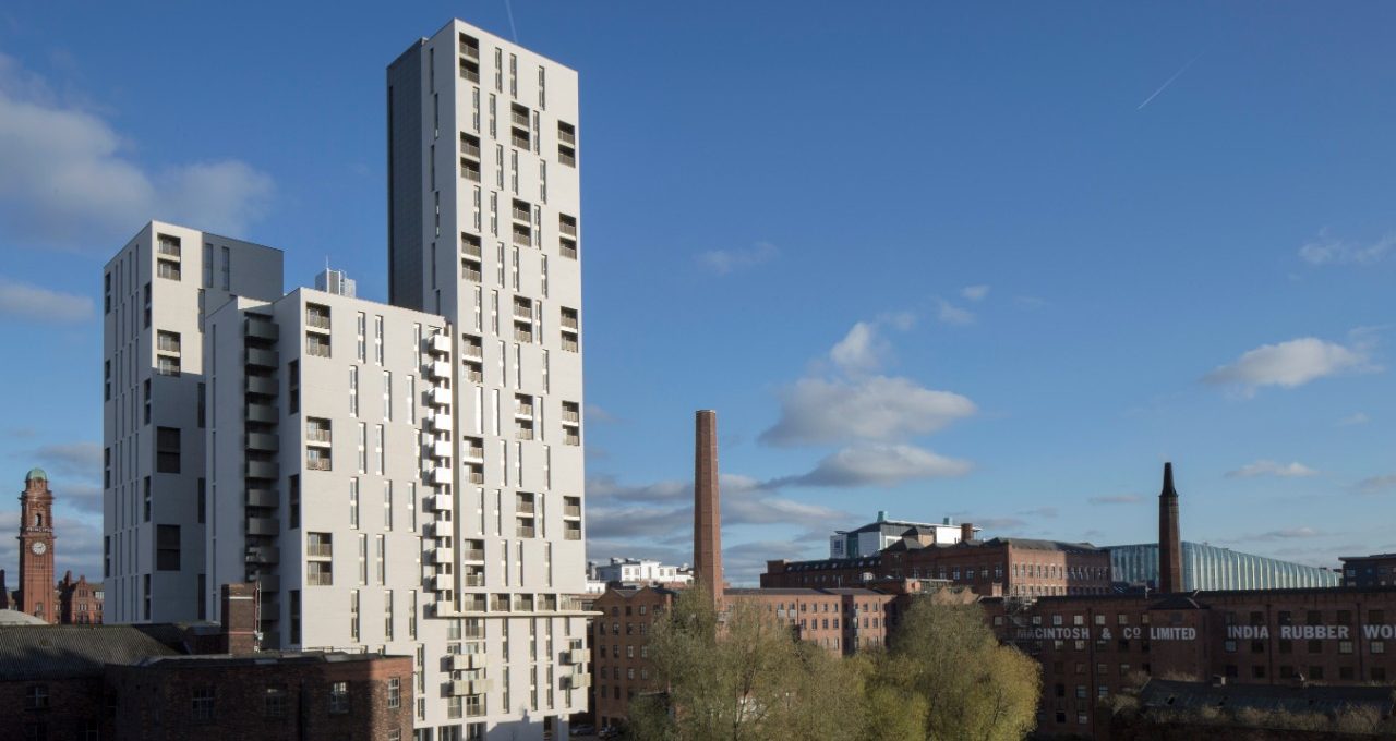 High-rise apartment building with white cladding against blue sky and cityscape