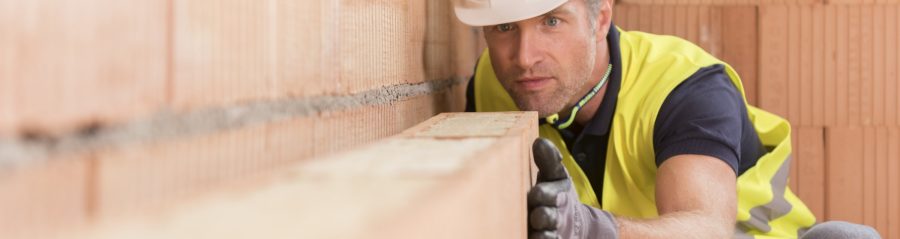 Man in protective gear laying Porotherm clay block walling