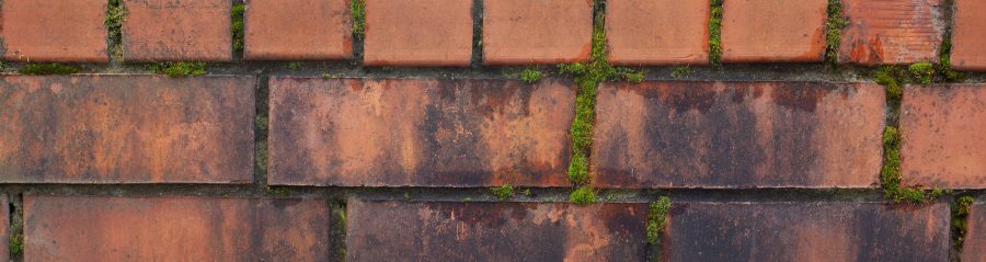 Dirt stained and mossy brickwork wall