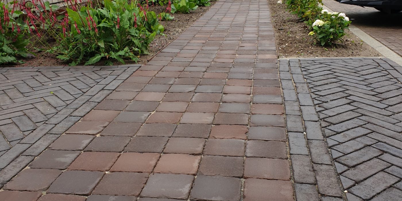 Two different style paving patterns meeting on a path